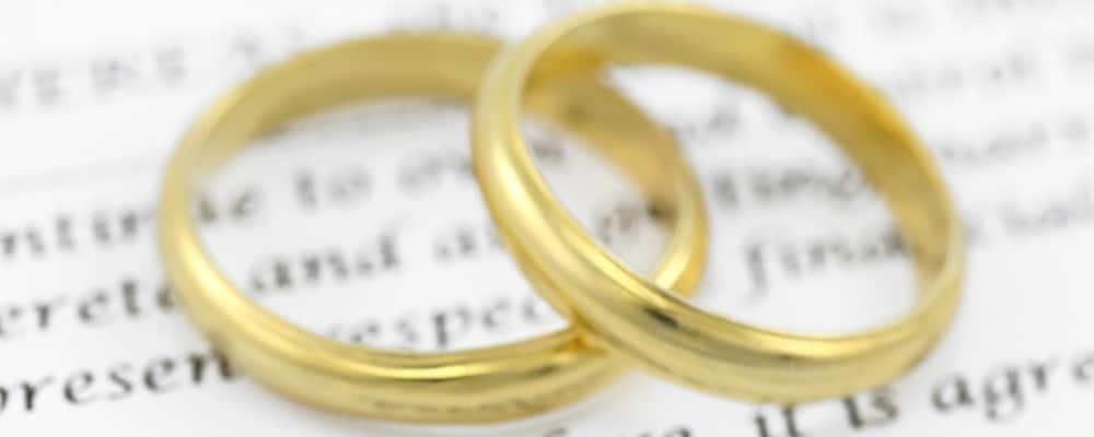 Two gold rings sitting on top of a prenuptial agreement