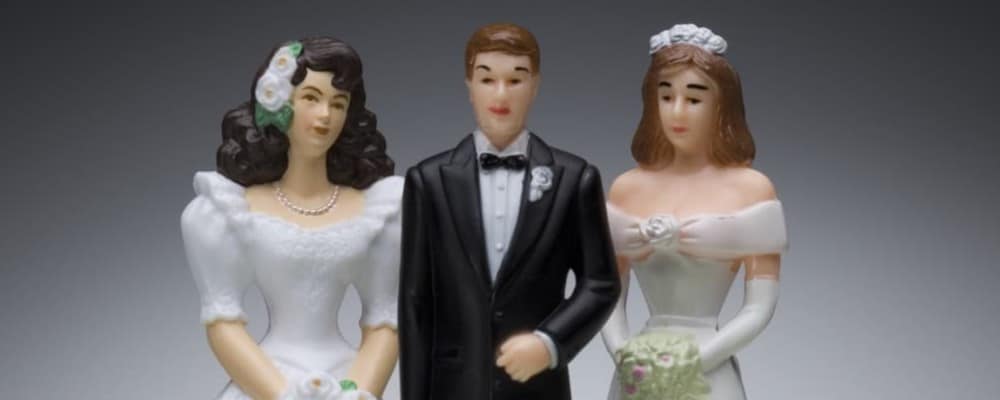 Groom and two bride figurines that go on top of a wedding cake